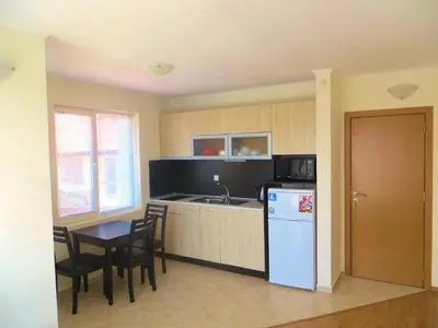 a small kitchen with a table and a refrigerator at Apartment in Azalia 2 complex in Nesebar
