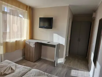 a bedroom with a desk and a tv on the wall at Lotos Apartments in Kiten