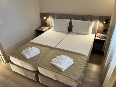 a bedroom with a bed with two white towels on it at Lotos Apartments in Kiten