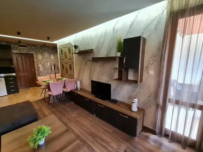 a living room with a television and a table with chairs at MitProt Panorama Bay 2 luks apartment ap.73 in Sveti Vlas