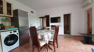 a kitchen with a table and a washing machine at Pomorie Beach Resort in Pomorie