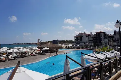 a swimming pool with umbrellas and people in the water at Apartment in the picturesque Oasis Resort & Spa in Lozenets