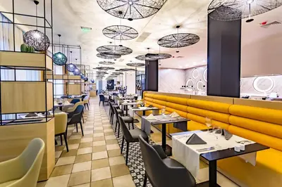 a restaurant with tables and chairs and a yellow wall at Royal Beach Apartament Hotel in Sunny Beach