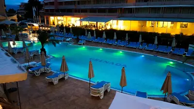 a large swimming pool with chairs and umbrellas at Grenada Apartaments in Sunny Beach
