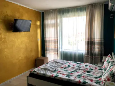 a bedroom with a bed with a television and a window at студио S in Primorsko