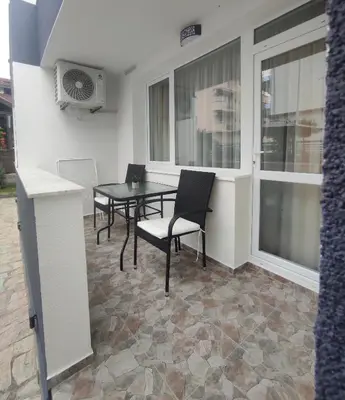 a patio with a table and chairs and windows at Вила TIMeS in Kiten