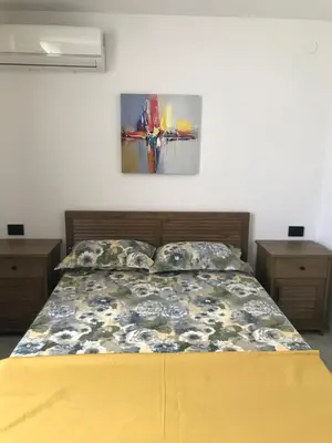 a bed in a room with two night stands and a painting on the wall at Вила TIMeS in Kiten