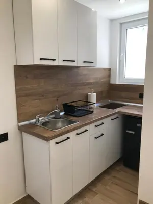 a kitchen with white cabinets and a sink and a window at Вила TIMeS in Kiten