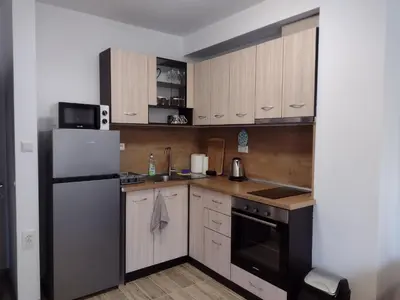 a small kitchen with a refrigerator and a microwave at Апартамент на къмпинг Градина in Chernomorets