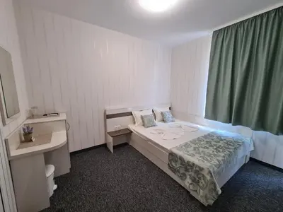a bedroom with a bed and a green curtain at Villa Yanevi in Ravda