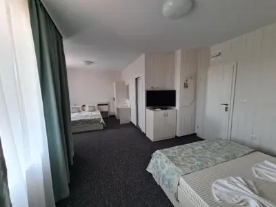 a hotel room with two beds and a television at Villa Yanevi in Ravda