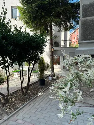 a garden with trees and a brick sidewalk at Markoni 1 in Burgas City