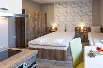 a bedroom with two beds and a kitchen with a table at BOLERO Suites in Varna City