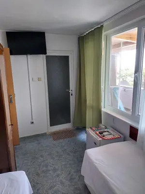 a room with two beds and a window and a door at Стаи за гости WEST in Pomorie