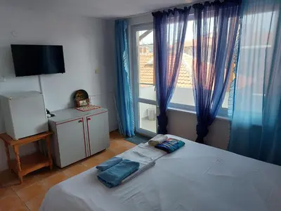 a bedroom with a bed and a large window at Стаи за гости WEST in Pomorie