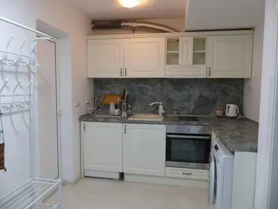 a kitchen with white cabinets and a sink and a refrigerator at Apartament HOLIDAY in Burgas City