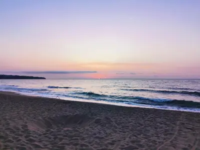 a beach at sunset with the ocean in the background at Апартамент Б003 в Обзор Бийч Резорт- море пред прозореца, плаж пред вратата !!! in Obzor