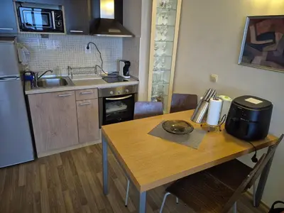 a kitchen with a wooden table and a kitchen with a sink at Апартамент Б003 в Обзор Бийч Резорт- море пред прозореца, плаж пред вратата !!! in Obzor