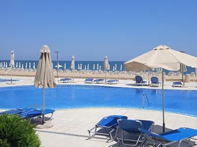 a swimming pool with chairs and umbrellas and the beach at Апартамент Б003 в Обзор Бийч Резорт- море пред прозореца, плаж пред вратата !!! in Obzor