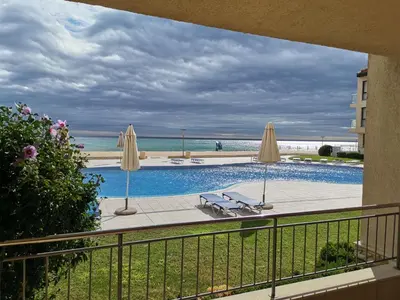 a view of a swimming pool with umbrellas and the beach at Апартамент Б003 в Обзор Бийч Резорт- море пред прозореца, плаж пред вратата !!! in Obzor