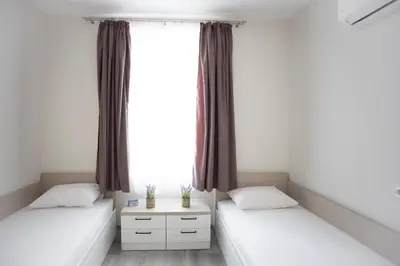 two beds in a room with a window at Апартамент за гости Стела in Burgas City