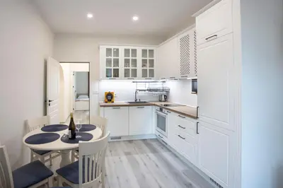 a kitchen with white cabinets and a table and chairs at Апартамент за гости Стела in Burgas City