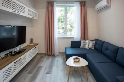 a living room with a blue couch and a tv at Апартамент за гости Стела in Burgas City