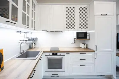 a white kitchen with white cabinets and a sink at Апартамент за гости Стела in Burgas City