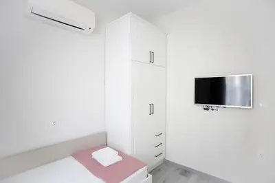 a white bathroom with a toilet and a tv at Апартамент за гости Стела in Burgas City