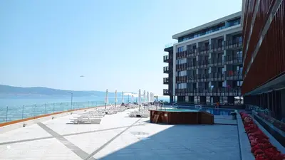 a building and a beach with chairs and a building at PARADISO 'В' 109 Large Cozy Studio NESEBAR in Nesebar