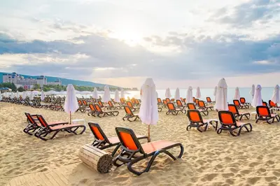a group of chairs and umbrellas on a beach at Sunny View Central - Menada Apartments in Sunny Beach