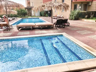 a swimming pool with two chaise lounges next to a house at Sunny View Central - Menada Apartments in Sunny Beach