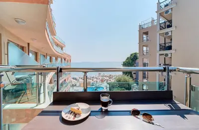 a table with a plate of food on a balcony at Beachfront Smart Homes by Marty's in Sunny Beach