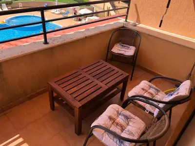 a balcony with two chairs and a bench and a swimming pool at Paradise Dreams apartment in Sveti Vlas