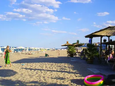 a woman walking on a beach with a frisbee on the sand at Апартаменти Атеа на плажа - Apartments Atea on the beach in Obzor
