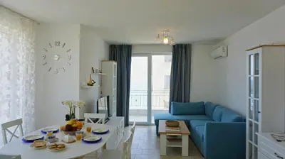 a living room with a blue couch and a table at Апартаменти Атеа на плажа - Apartments Atea on the beach in Obzor