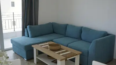 a blue couch in a living room with a table at Апартаменти Атеа на плажа - Apartments Atea on the beach in Obzor
