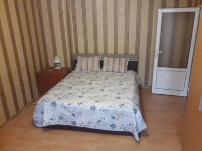 a bedroom with a bed with a floral bedspread at Удобство in Burgas City
