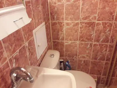 a bathroom with a white toilet and a sink at Удобство in Burgas City