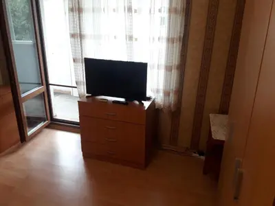 a television on a dresser in front of a window at Удобство in Burgas City