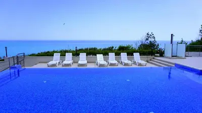 a swimming pool with lounge chairs and the ocean at Бяла Клиф Форест - Byala Cliff Forest in Byala