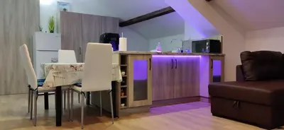a kitchen with a table with white chairs and purple lighting at Apartment 7 in Tsarevo