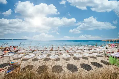 a beach with many umbrellas and people in the water at Fort Noks - Menada Apartments in Sveti Vlas