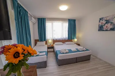 a hotel room with two beds and a vase of flowers at Hotel Zonya in Sunny Beach