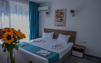 a bedroom with a bed with a vase of sunflowers at Hotel Zonya in Sunny Beach