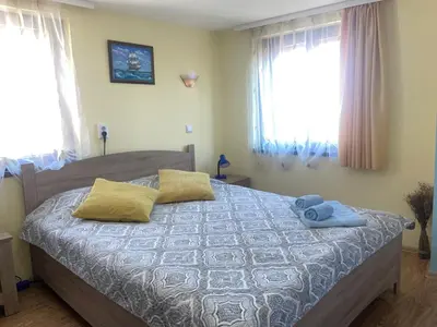 a bedroom with a bed with two pillows and two windows at Къща за гости ЕЛЕНИ in Sozopol