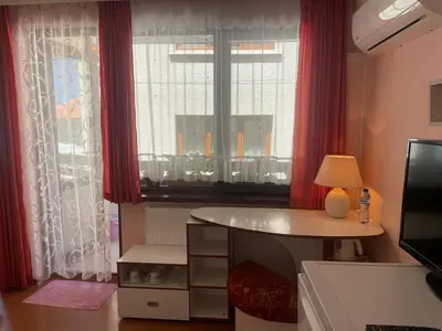 a room with a table and a window with red curtains at Къща за гости ЕЛЕНИ in Sozopol