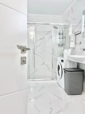 a white bathroom with a shower and a sink at Modern Apartment for 4 Guests Sea View & Free Parking in Pomorie