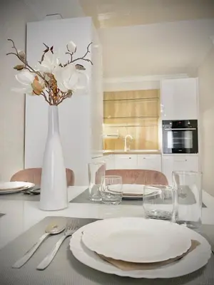 a table with a white plate and a vase with flowers at Modern Apartment for 4 Guests Sea View & Free Parking in Pomorie