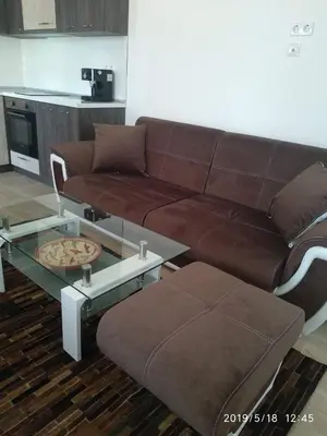 a living room with a brown couch and a table at Акротирия Фешева in Nesebar